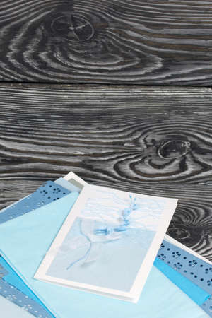 Greeting card with elements of blue shades. Materials for making postcards. On pine planks in black.