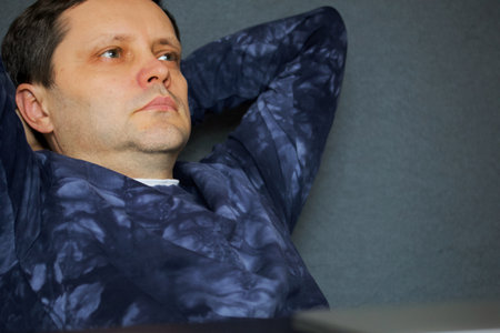Portrait of a man with hands behind his head. Sits with a pensive look. Close-up shot.の写真素材