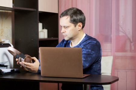 A man in home clothes works at a laptop. Puts headphones on his head.
