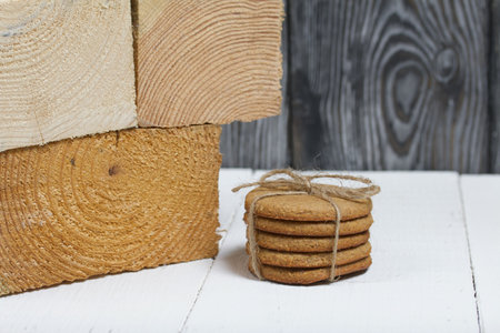 Gingerbread cookies tied with twine. Nearby are wooden blocks. On boards painted white.の写真素材