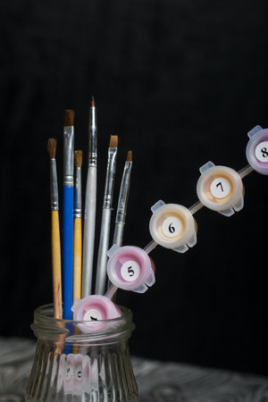 Brushes and paints for painting in a jar. On a black background.