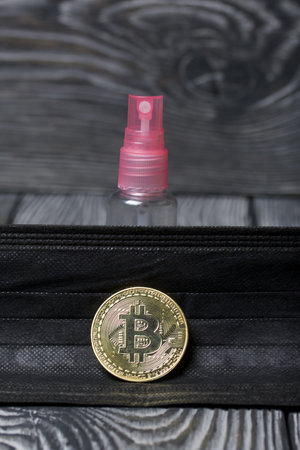 Bitcoin on black pine boards. Nearby is a medical mask and an antiseptic spray.