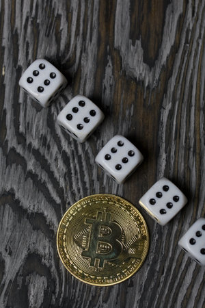 Bitcoin on black pine boards. Dice are scattered nearby.の写真素材