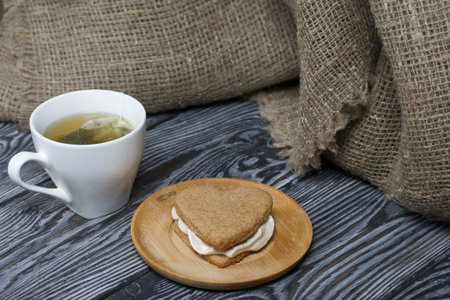 Gingerbread cookie with marshmallows. Marshmallow sandwich on black pine boards. Nearby is a cup of tea.の写真素材