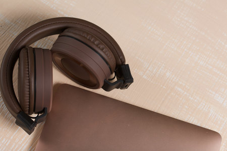 Fragment of a pink notebook. Nearby are wireless headphones in brown. The surface is painted in...