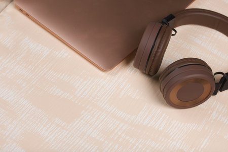 Fragment of a pink notebook. Nearby are wireless headphones in brown. The surface is painted in...