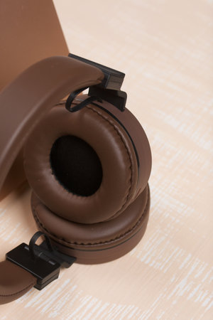 Fragment of an open pink laptop. Nearby are wireless headphones in brown. The surface is painted in white and beige.の写真素材