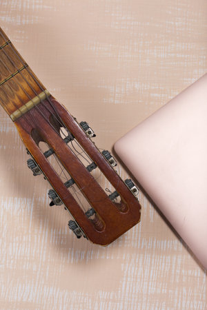 Fragment of acoustic guitar and notebook. Against a background painted in white and beige.