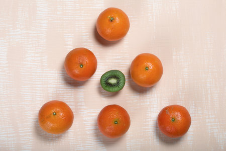 Several orange tangerines. Kiwi fruit cut in half. Juicy green flesh is visible. Lie on a beige surface.の写真素材