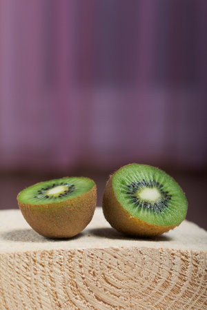Kiwi fruit cut in half. Juicy green flesh is visible. Lies on a wooden block.の写真素材