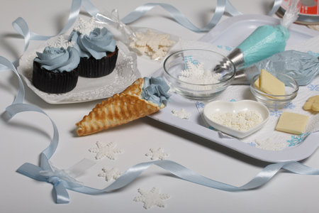 Muffin with cream cheese cream. Decorated with a marshmallow snowflake. Nearby waffle cones and ingredients for their preparation.の写真素材