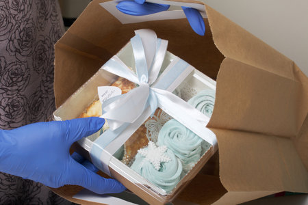 A woman in rubber gloves holds a package of homemade marshmallows. Puts it in a gift bag. Close-up...