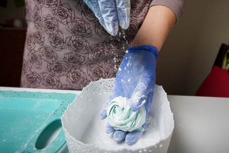 Woman in rubber gloves makes marshmallows. Sprinkles it with powdered sugar. Dessert lies on the...