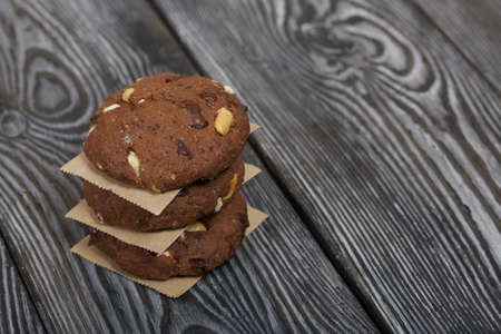 Oatmeal cookies with peanuts and chocolate. Folded in a column and laid out with paper. On pine...