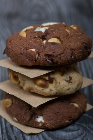 Oatmeal cookies with peanuts and chocolate. Folded in a column and laid out with paper. On pine...