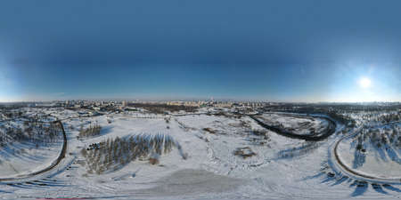 Urban winter landscape from above. Multi-storey buildings and trees in the city park are visible....