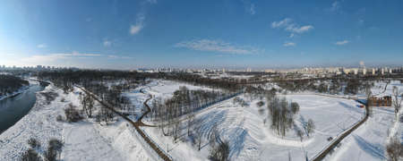 Urban winter landscape from above. Multi-storey buildings and trees in the city park are visible....