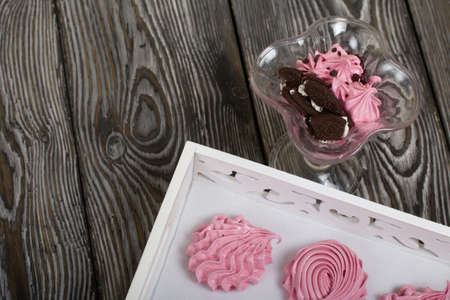 Cooked marshmallows on a white wooden tray. Stands on wooden planks. Nearby is a bowl with...