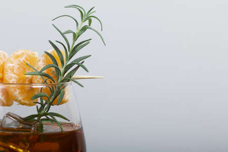 Alcoholic cocktail. Garnished with rosemary slices and tangerine wedges. Close-up shot.の写真素材