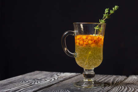 Cocktail with sparkling wine and sea buckthorn. Sea buckthorn bellini. Decorated with thyme sprigs.