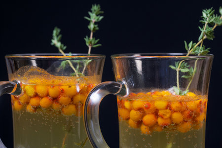 Cocktail with sparkling wine and sea buckthorn. Sea buckthorn bellini. Decorated with thyme sprigs.の写真素材