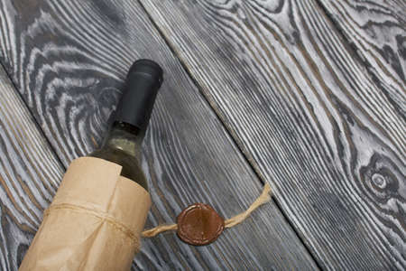 Alcohol bottle. Wrapped in paper. Lies on pine boards.の写真素材