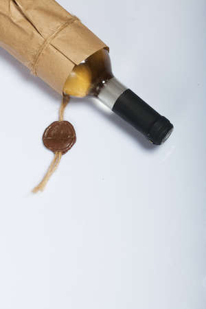 Alcohol bottle. Wrapped in paper. On a white surface.の写真素材