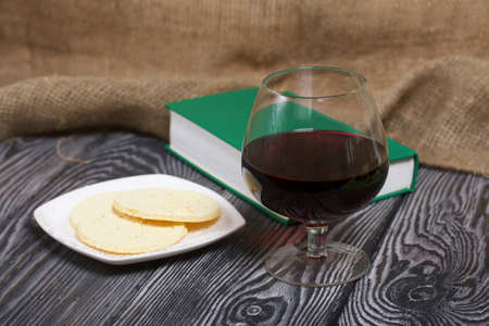 A glass of dry red wine and broken unleavened bread lie on a plate. To celebrate the Lord's Supper. Nearby lies the Bible.の写真素材