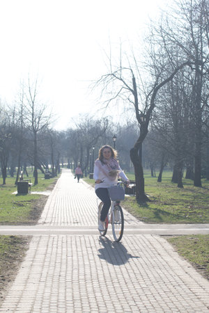 Girl on a bike ride in a spring park. Stands with a bike.