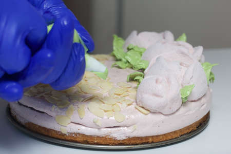 A woman prepares a marshmallow cake. Makes green leaves on roses from marshmallows. Works with a...