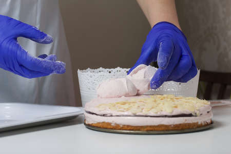 A woman prepares a marshmallow cake. Makes roses from marshmallows for decoration and places on the...