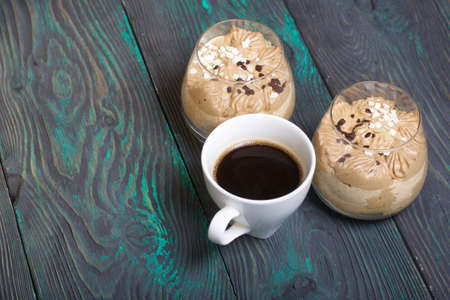 Peanut Trifle decorated with black and white chocolate. Nearby is a cup of coffee. Stands on pine...