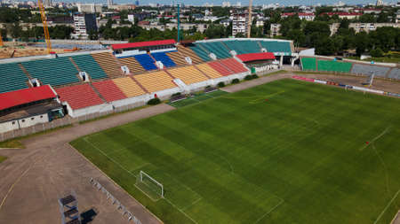 Football stadium in the city park. A green field and stands are visible, painted in different colors. Close-up shot. Aerial photography.のeditorial素材