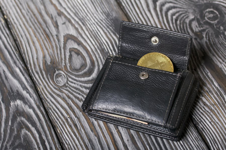 Cryptocurrency coin in an open wallet. On brushed pine boards.の写真素材