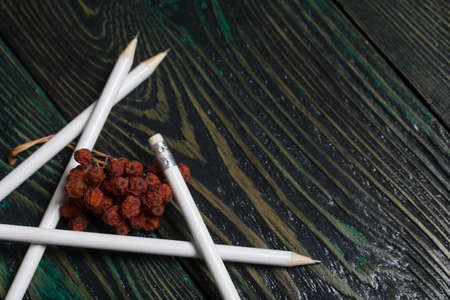 A set of white pencils for school. They lie on pine boards. Nearby autumn maple leaves.