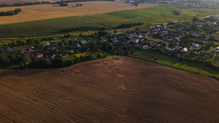 A small village surrounded by agricultural fields. Filmed at sunset. Aerial photography.の写真素材