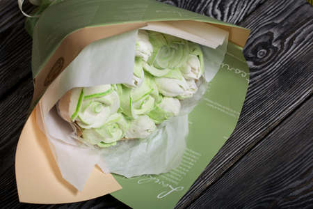 Marshmallow bouquet in paper packaging. Zephyr in the form of roses and tulips. In light green colors. Close-up shot.の写真素材