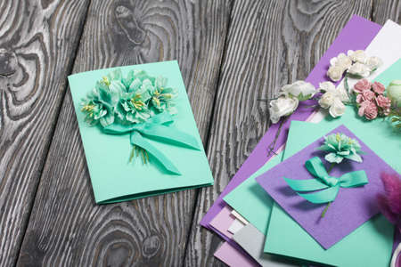 Homemade handmade postcard. Nearby there are materials for making postcards. On black pine boards.の写真素材