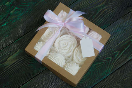 Homemade marshmallow in a gift box. Tied with a ribbon tied to a bow. On black-green pine boards.の写真素材