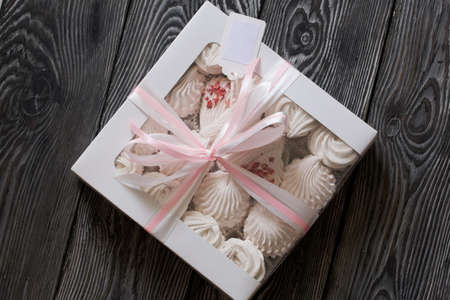 Homemade marshmallow in a gift box. Tied with a ribbon tied to a bow. On black pine boards.の写真素材