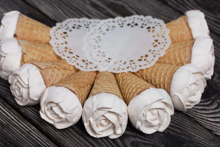 Homemade marshmallows are spread out on the table surface. Zephyr in a waffle cone. Made in the shape of a rose. Close-up shot.の写真素材