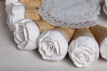 Homemade marshmallows are spread out on the table surface. Zephyr in a waffle cone. Made in the shape of a rose. Close-up shot.の写真素材