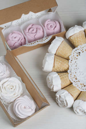 Homemade marshmallows are spread out on the table surface. Zephyr in a waffle cone. Made in the shape of a rose. Close-up shot.の写真素材