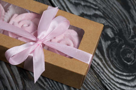 Homemade marshmallows in craft packaging. Zephyr in the form of a rose. Against the background of pine boards.の写真素材