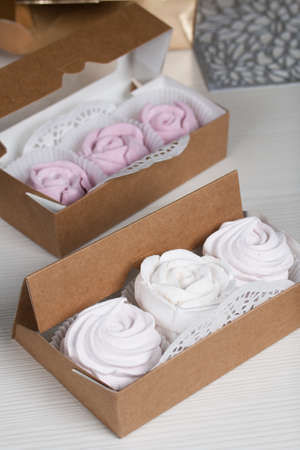 Homemade marshmallows in craft packaging. Zephyr in the form of a rose. Against the background of pine boards.の写真素材