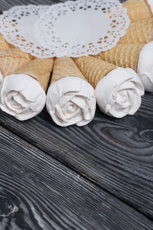 Homemade marshmallows are spread out on the table surface. Zephyr in a waffle cone. Made in the shape of a rose. Close-up shot.の写真素材