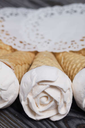 Homemade marshmallows are spread out on the table surface. Zephyr in a waffle cone. Made in the shape of a rose. Close-up shot.の写真素材