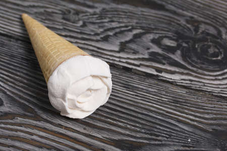 Homemade marshmallows are spread out on the table surface. Zephyr in a waffle cone. Made in the shape of a rose. Close-up shot.の写真素材
