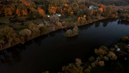Flight over the autumn park. Trees with yellow autumn leaves are visible. Park buildings are visible. The park pond is visible. Aerial photography.の写真素材