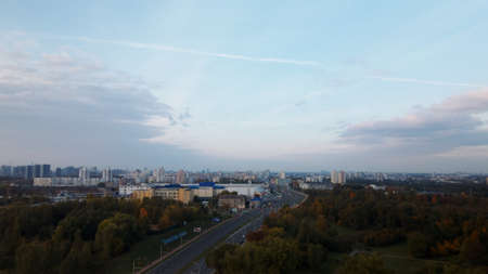 Flight over the autumn park. On the horizon there is a blue sky with clouds and city houses. The...